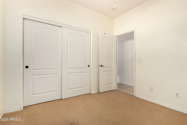 unfurnished bedroom with light carpet and a closet