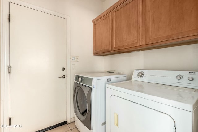 laundry room with cabinets, light tile patterned floors, and washer and dryer