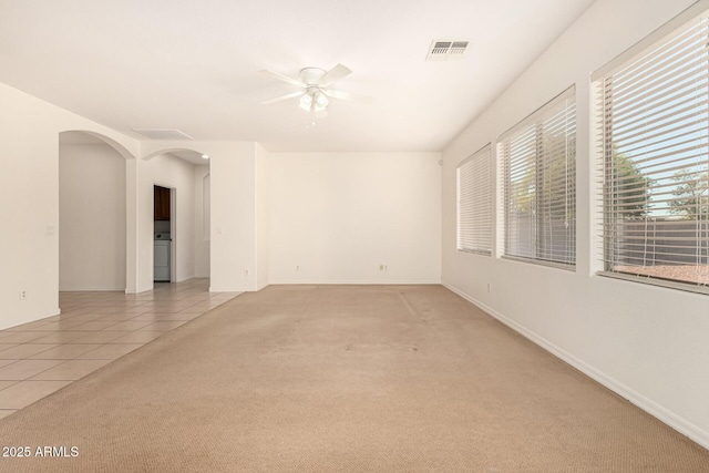 spare room featuring washer / clothes dryer, light carpet, and ceiling fan