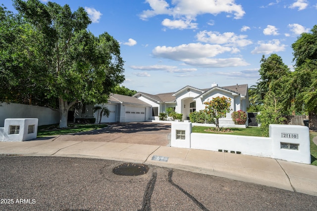 view of front of property with driveway, a garage, fence, and stucco siding