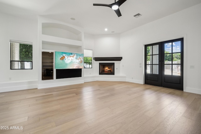 unfurnished living room featuring light wood finished floors, a warm lit fireplace, ceiling fan, recessed lighting, and baseboards