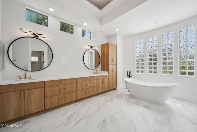 bathroom featuring a freestanding bath, recessed lighting, double vanity, and marble finish floors