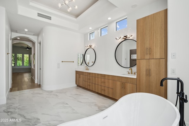 full bath with a freestanding tub, marble finish floors, recessed lighting, double vanity, and baseboards