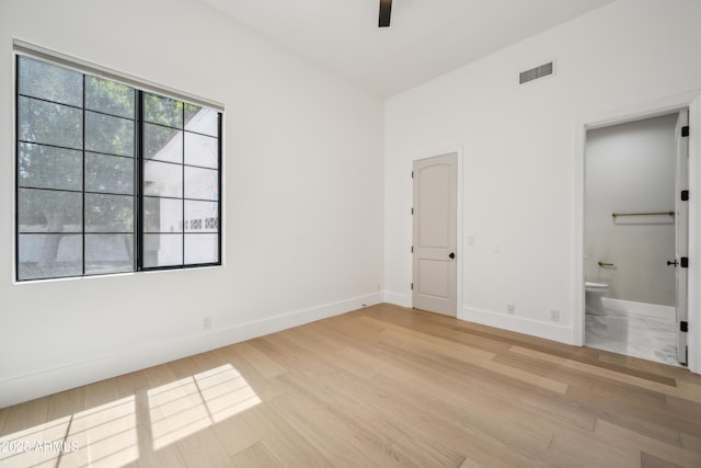 unfurnished bedroom with baseboards, light wood finished floors, ensuite bath, and a ceiling fan