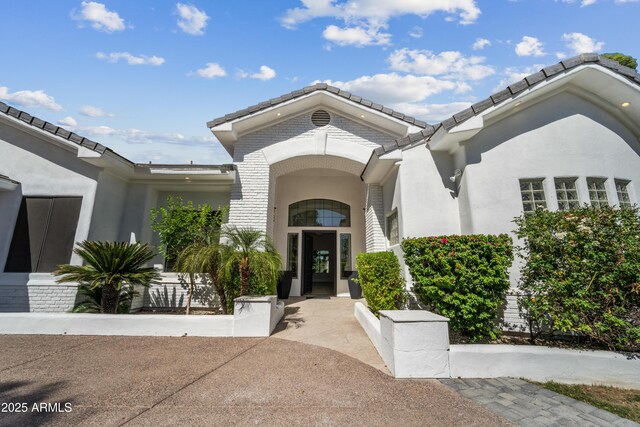 property entrance featuring stucco siding and a tiled roof