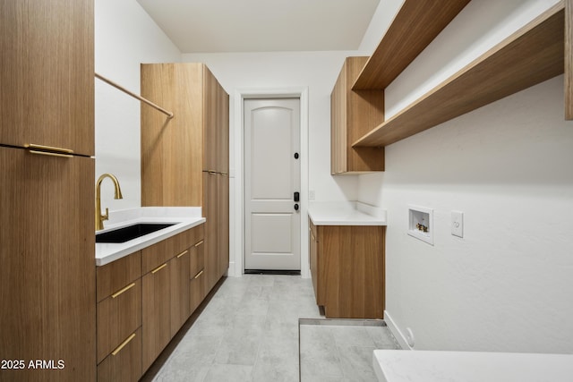 clothes washing area with a sink, washer hookup, and baseboards