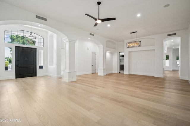 unfurnished living room with a ceiling fan, light wood-type flooring, recessed lighting, a chandelier, and arched walkways