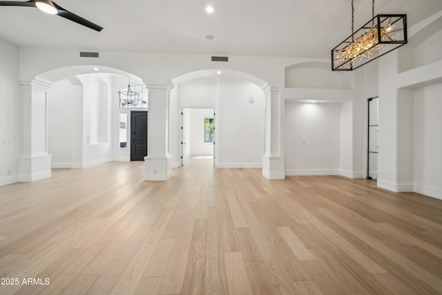 unfurnished living room featuring light wood-type flooring, ceiling fan, a chandelier, and recessed lighting