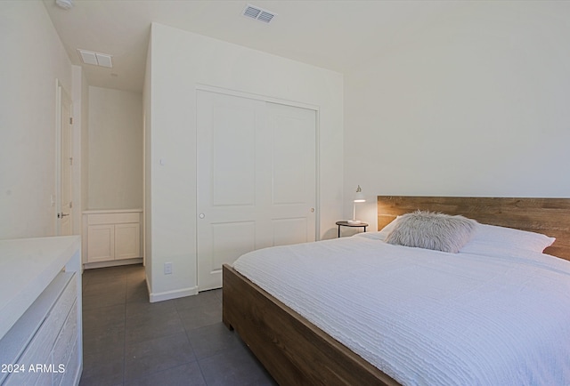 bedroom with a closet and dark tile floors