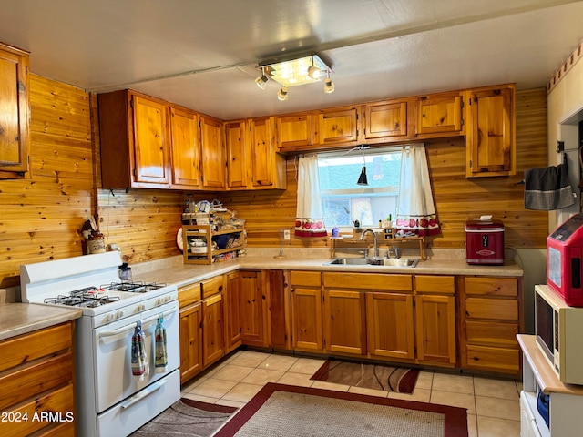 kitchen featuring light tile patterned flooring, white appliances, sink, and wood walls