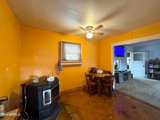 carpeted dining room with a wood stove, a textured ceiling, and ceiling fan