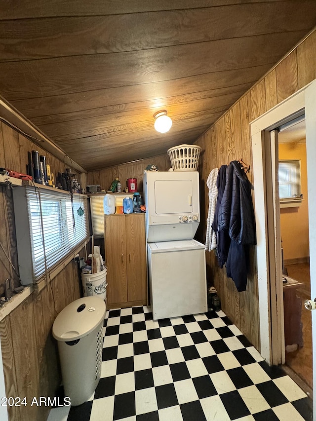 washroom featuring laundry area, light floors, wooden walls, wood ceiling, and stacked washer / drying machine