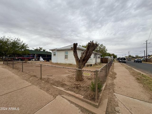 view of side of home featuring fence and metal roof