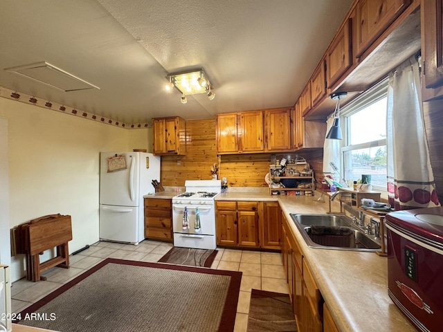 kitchen with white appliances, light tile patterned floors, a sink, and light countertops
