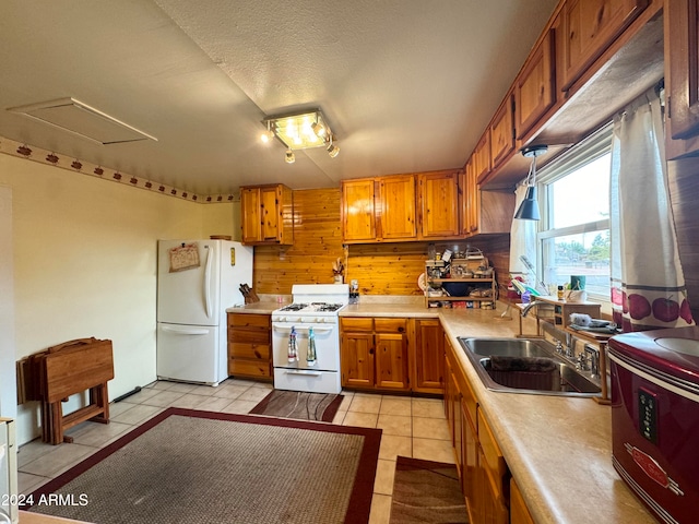 kitchen featuring sink, light tile patterned floors, a textured ceiling, and white appliances