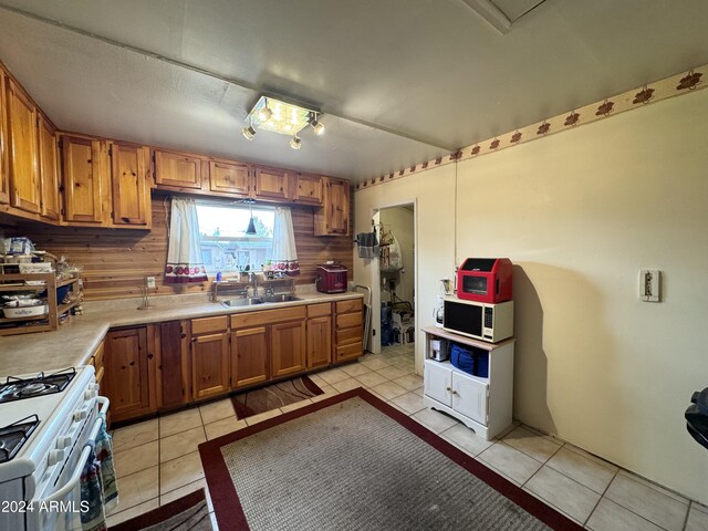 kitchen with white appliances, light tile patterned flooring, and brown cabinetry