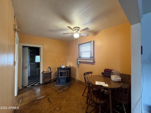 dining area with a wood stove, a textured ceiling, and ceiling fan