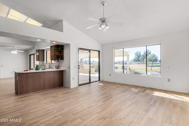 unfurnished living room featuring light wood-type flooring, ceiling fan, lofted ceiling, and sink