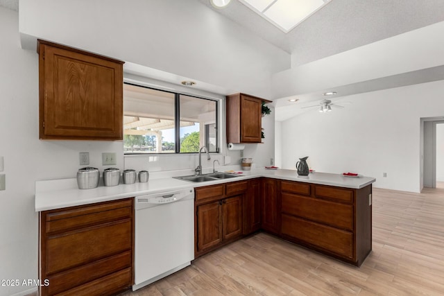 kitchen featuring white dishwasher, sink, kitchen peninsula, and light hardwood / wood-style floors