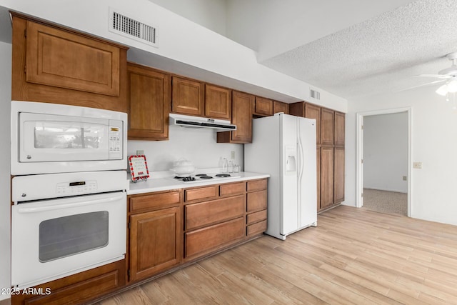 kitchen with ceiling fan, white appliances, a textured ceiling, and light wood-type flooring