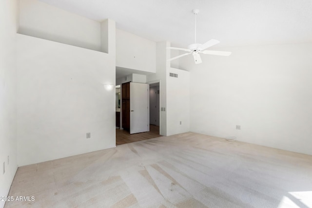 carpeted spare room with ceiling fan and high vaulted ceiling