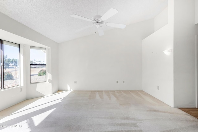 carpeted empty room with ceiling fan, a textured ceiling, and lofted ceiling