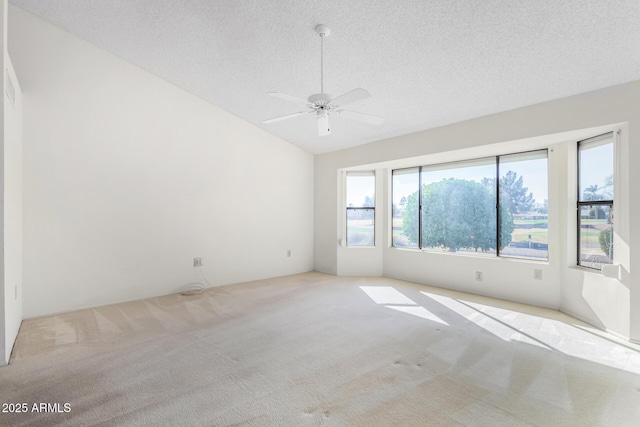 carpeted spare room featuring ceiling fan, vaulted ceiling, and a textured ceiling