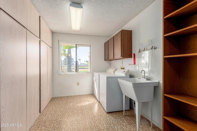 clothes washing area featuring cabinets, a textured ceiling, and washer and clothes dryer