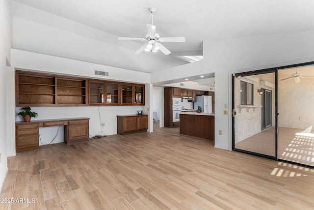 unfurnished living room featuring built in desk, ceiling fan, light wood-type flooring, and lofted ceiling