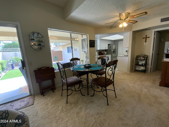 carpeted dining space featuring plenty of natural light, ceiling fan, and a textured ceiling