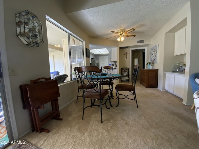 carpeted dining room with a textured ceiling and ceiling fan