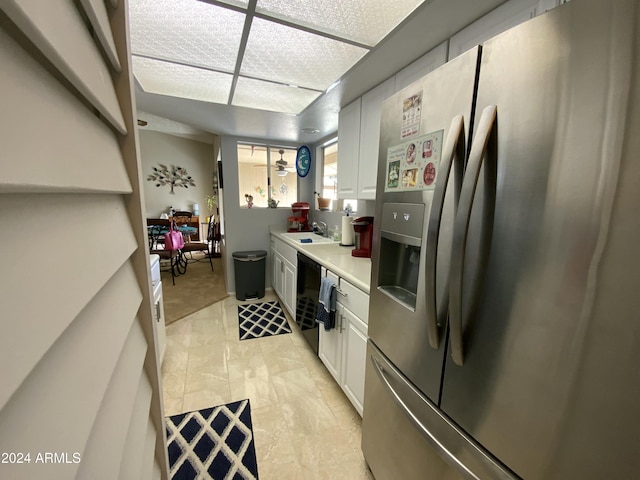 kitchen with stainless steel refrigerator with ice dispenser, white cabinetry, and sink