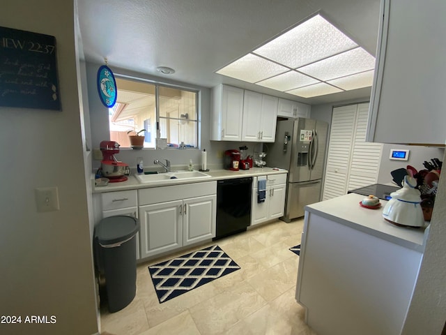 kitchen featuring stainless steel fridge, black dishwasher, white cabinetry, and sink