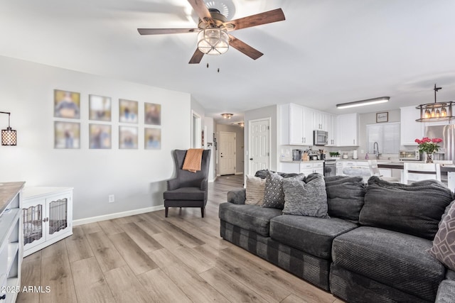 living room featuring sink, ceiling fan, and light hardwood / wood-style flooring