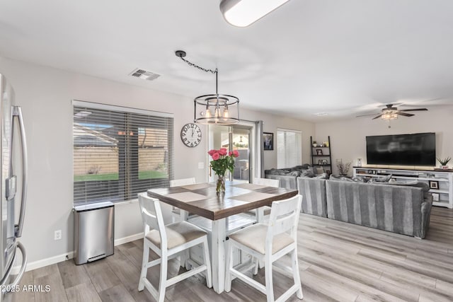 dining space featuring ceiling fan with notable chandelier and light hardwood / wood-style flooring