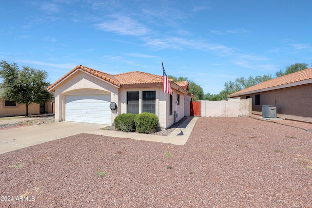 view of front facade featuring stucco siding, driveway, a tile roof, an attached garage, and central AC unit