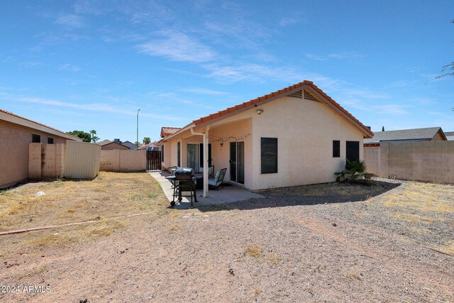 rear view of house featuring a tiled roof, a patio area, a fenced backyard, and stucco siding