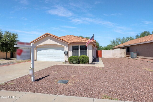 view of front of home with an attached garage, a tile roof, central AC unit, stucco siding, and driveway