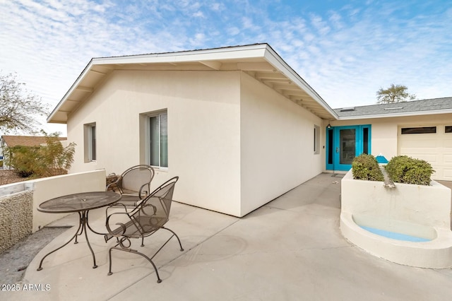 exterior space featuring a garage, a patio area, and stucco siding