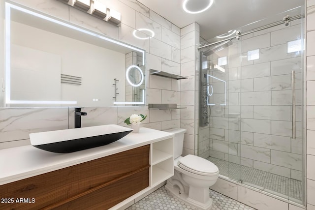 full bath featuring a stall shower, toilet, tile patterned floors, vanity, and tile walls