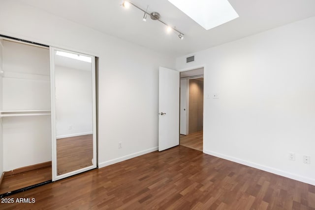 unfurnished bedroom featuring a skylight, baseboards, visible vents, and wood finished floors