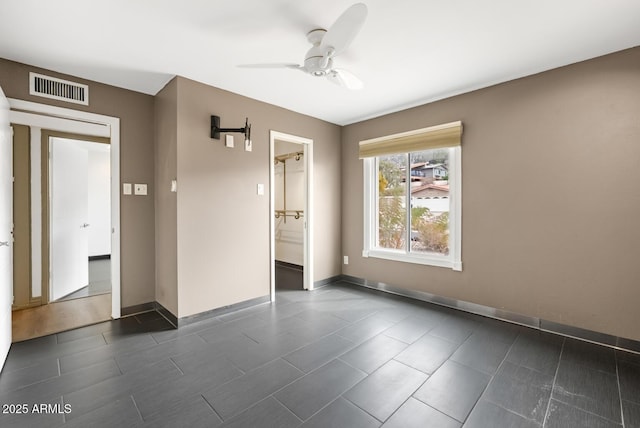 empty room featuring a ceiling fan, visible vents, and baseboards