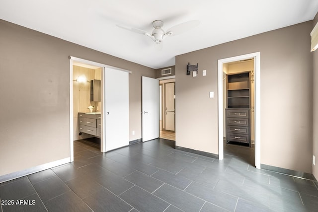 unfurnished bedroom featuring a spacious closet, connected bathroom, visible vents, and baseboards