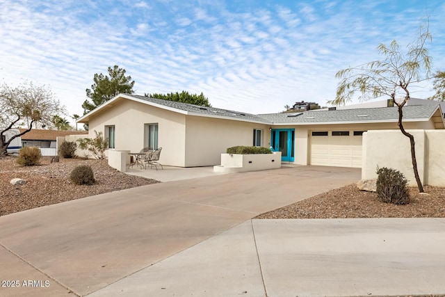 single story home with a garage, driveway, and stucco siding