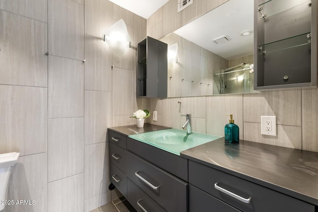 bathroom with visible vents, decorative backsplash, an enclosed shower, vanity, and tile walls