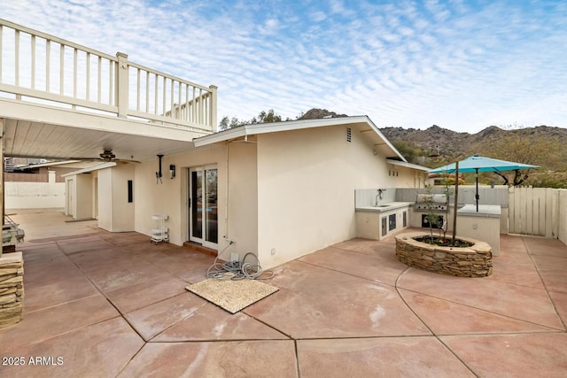 view of patio / terrace featuring fence, an outdoor kitchen, and ceiling fan