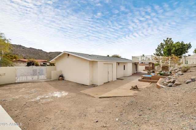 rear view of property featuring a patio area, a gate, fence, and stucco siding