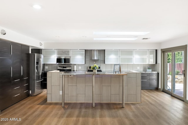 kitchen with stainless steel appliances, wall chimney exhaust hood, and modern cabinets