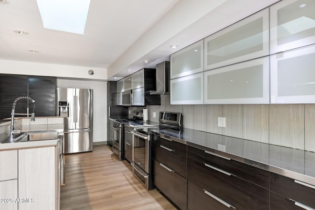 kitchen with appliances with stainless steel finishes, modern cabinets, and wall chimney range hood