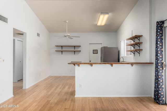 5135 E Evergreen St Unit 1166, Mesa, AZ 85205 - kitchen featuring freestanding refrigerator, open shelves, ceiling fan, a kitchen bar, and light wood-type flooring